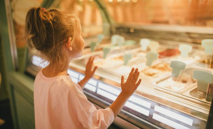 bambina che guarda vetrina dei gelati
