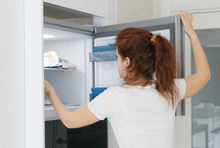 donna si spalle con freezer aperto