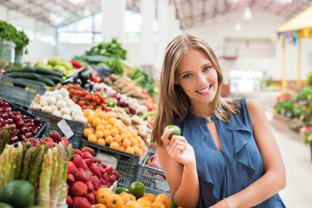 donna con un frutto in mano nel reparto ortufrutta