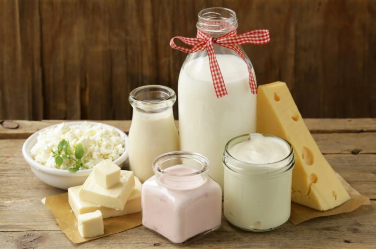 bottiglia di latte e accanto formaggi e vasetti di yogurt