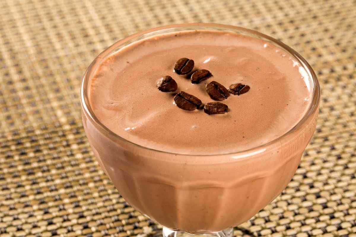 coppetta con crema di caffè e chicchi di caffè