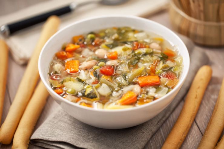 piatto di minestrone con accanto dei grissini