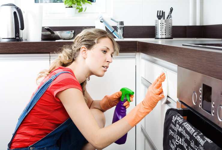 donna pulisce i pensili della cucina