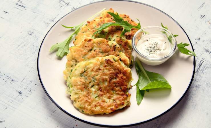 piatto di frittelle di zucchine con salsa