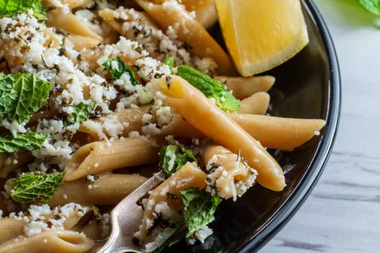 primo piano di pasta condita con menta e formaggio