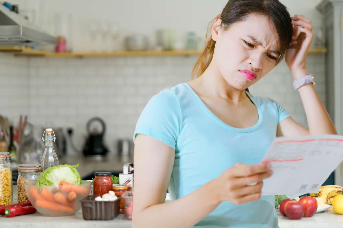 Una donna che consulta una bolletta in cucina