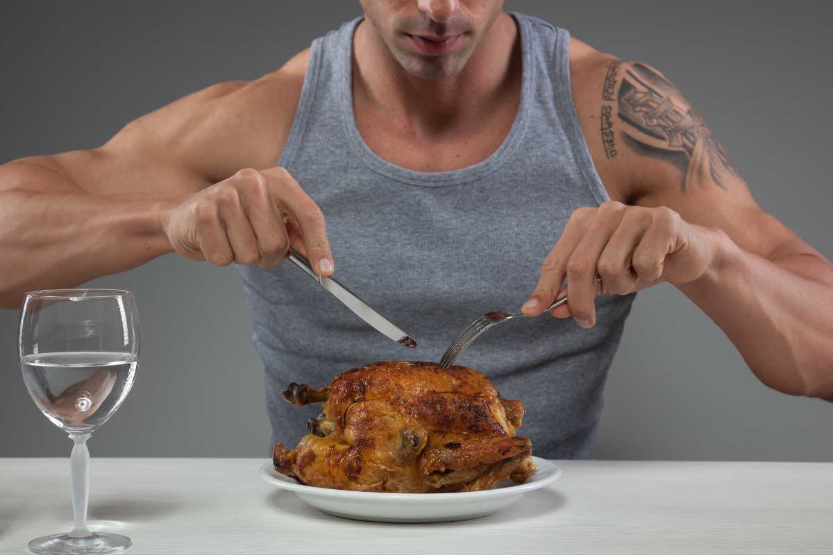 Un uomo che mangia del pollo per una cena con sole proteine