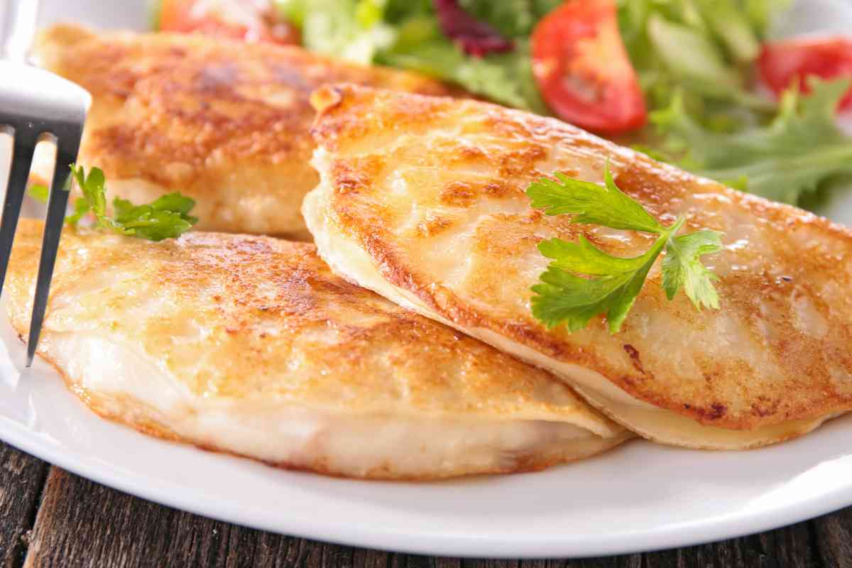 Crespelle con farina di ceci farcite con prosciutto cotto e mozzarella in un piatto