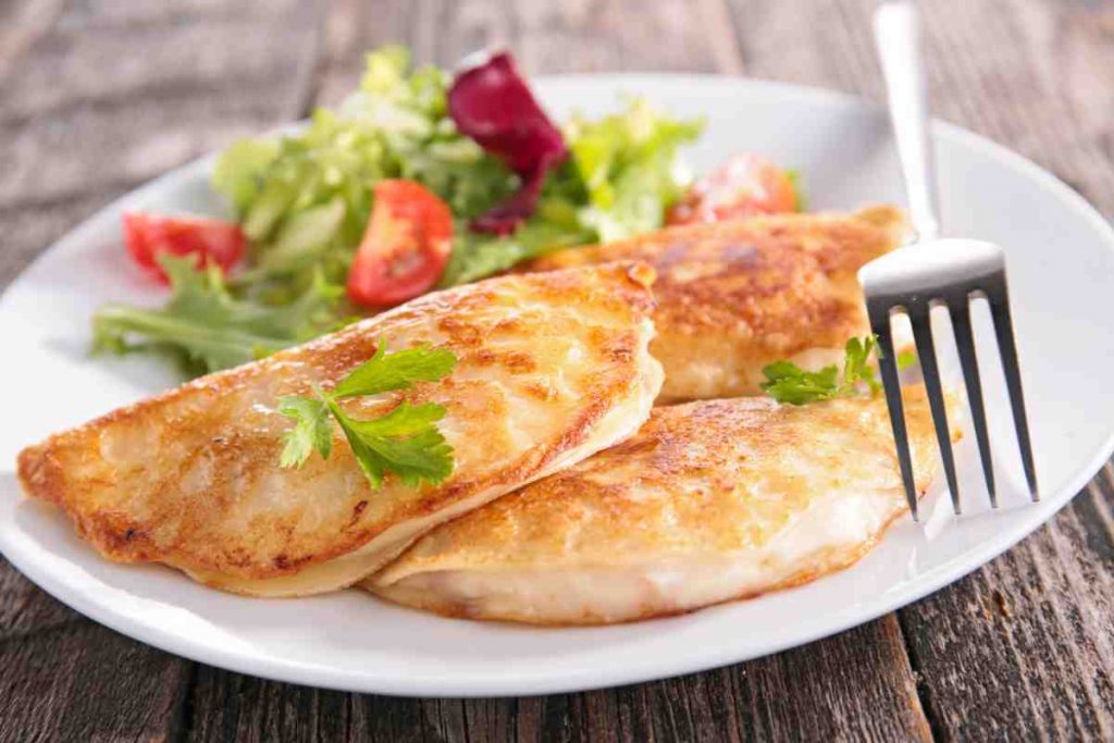Crespelle di farina di ceci farcite con prosciutto cotto e mozzarella in un piatto