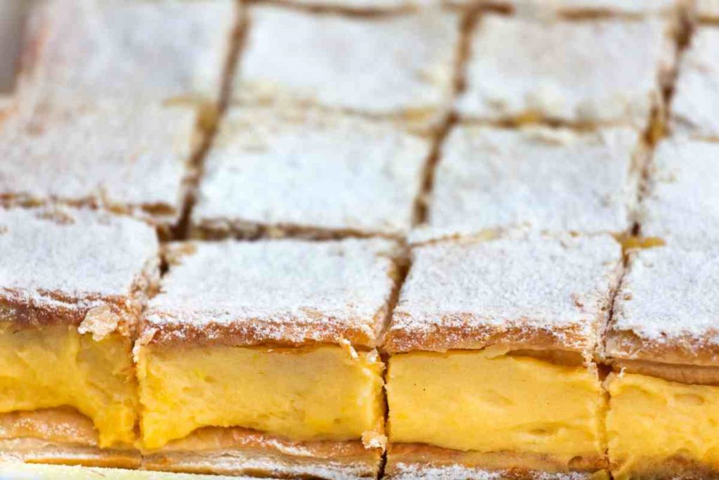 Dolcetti di pasta sfoglia con crema al limone tagliati a quadrotti cosparsi di zucchero a velo