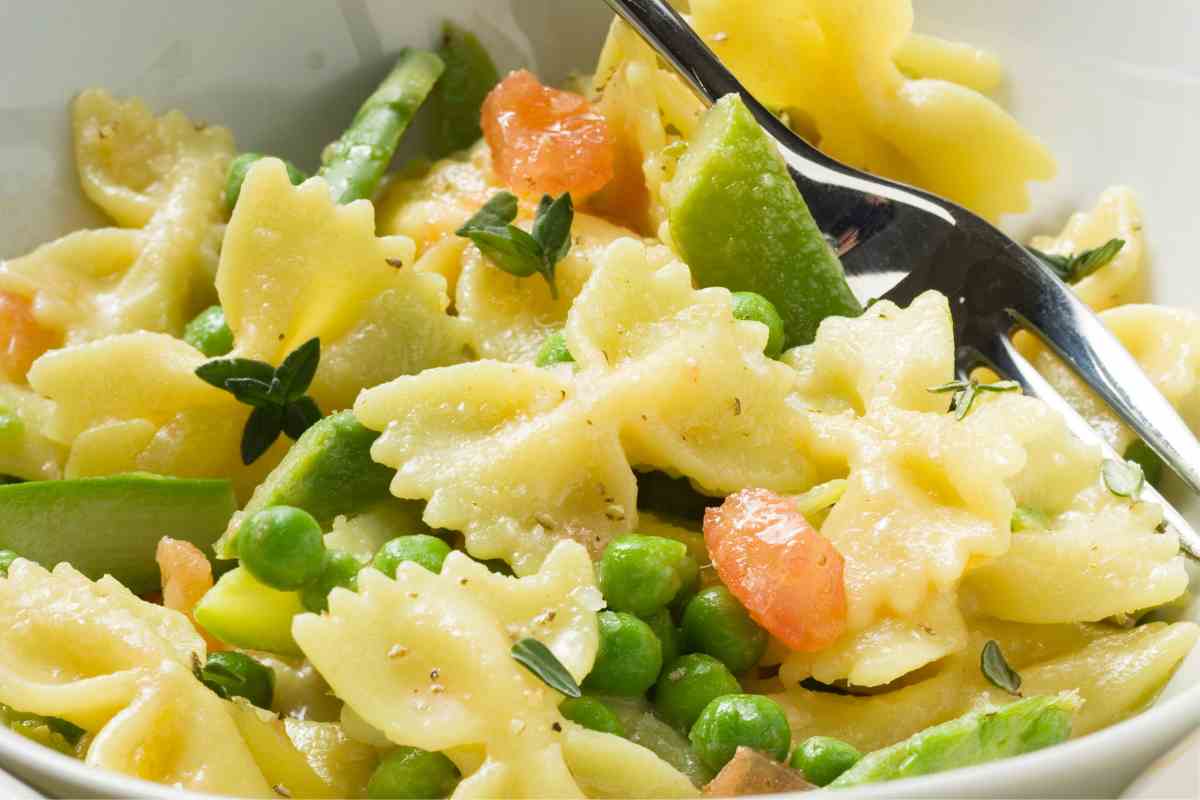 piatto di farfalle salmone e verdurine con una forchetta in mezzo