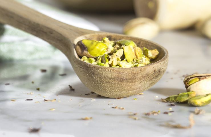 Della granella al pistacchio in un mestolo di legno
