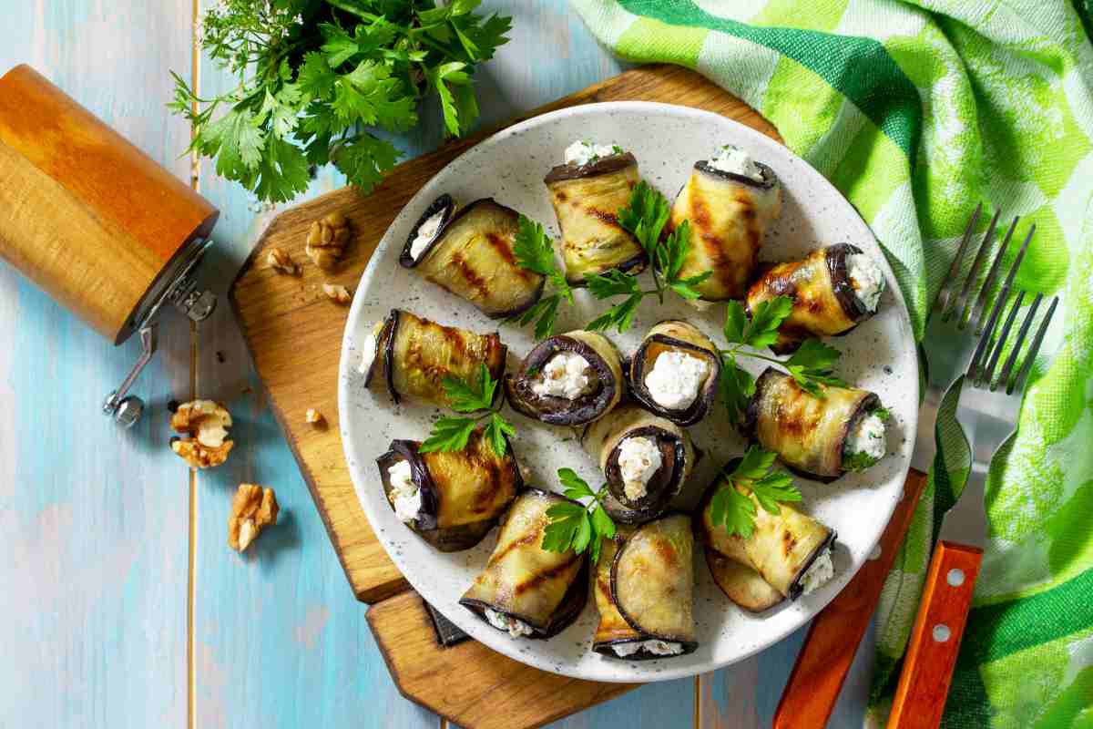 Un piatto pieno di involtini di melanzane con robiola e noci