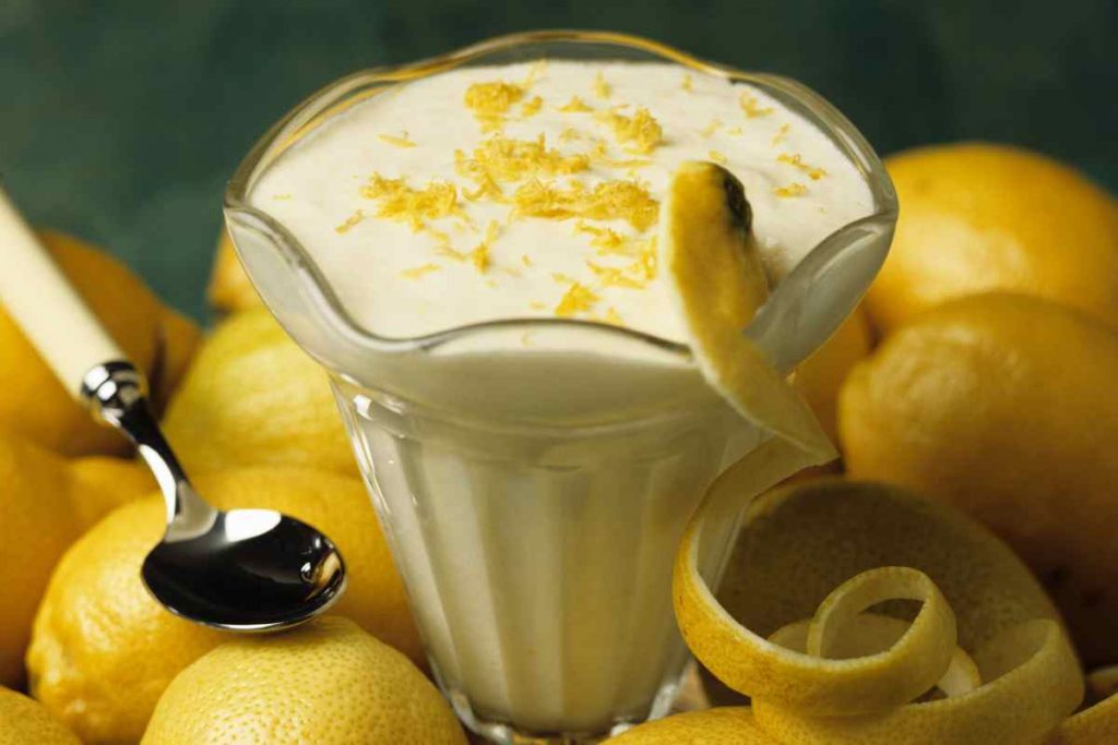 Mousse al limone e yogurt in una coppa con limoni intorno