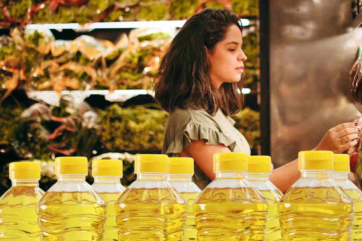 Una donna che fa la spesa e delle bottiglie di olio