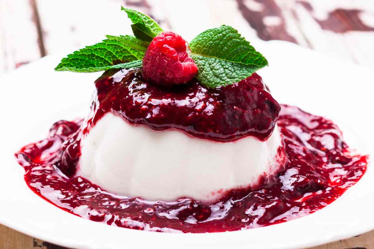 piattino con panna cotta coperta da salsa ai lamponi