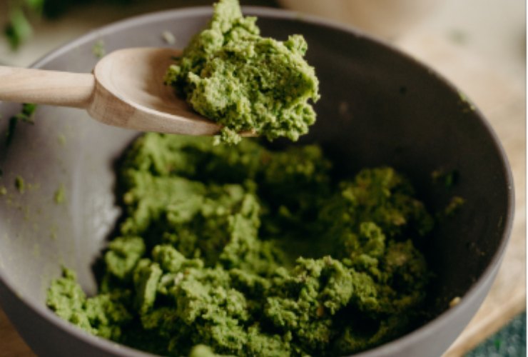 Cucchiaino di pesto di basilico in una terrina