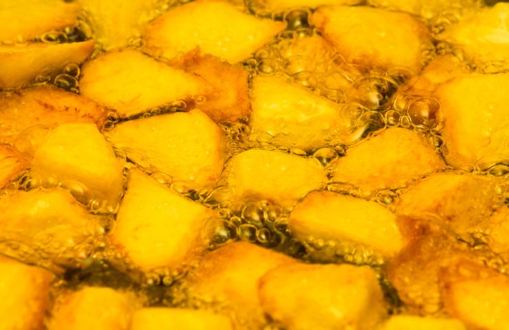 Patate tagliate che friggono in una padella