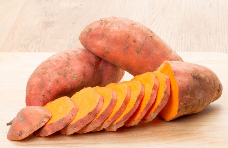 Tre patate dolci delle quali una tagliata a fette