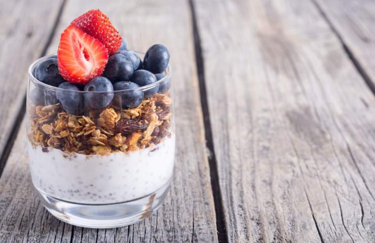 Un vasetto di yogurt con frutti di bosco e cereali