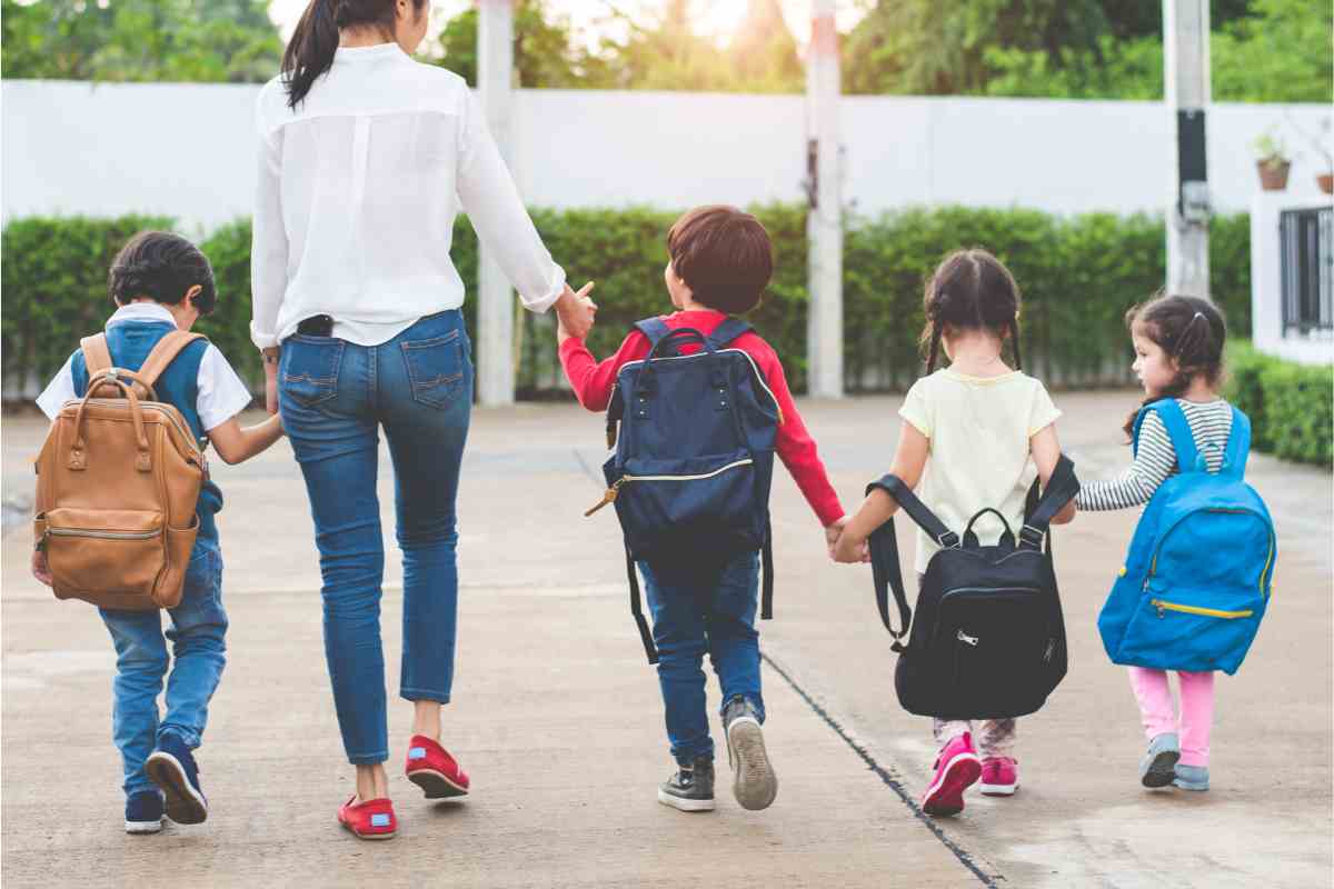 Una donna e dei bambini che vanno a scuola