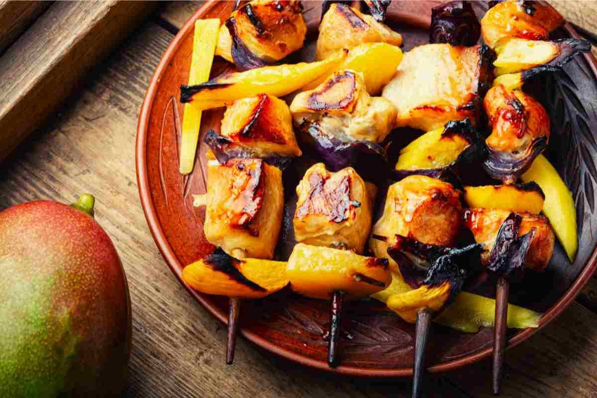 Un piatto con spiedini di pollo con mango e spezie