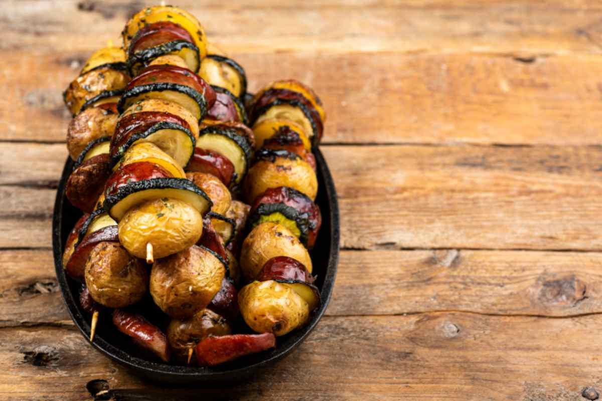 Spiedini di patate, salsiccia e zucchine in una pirofila