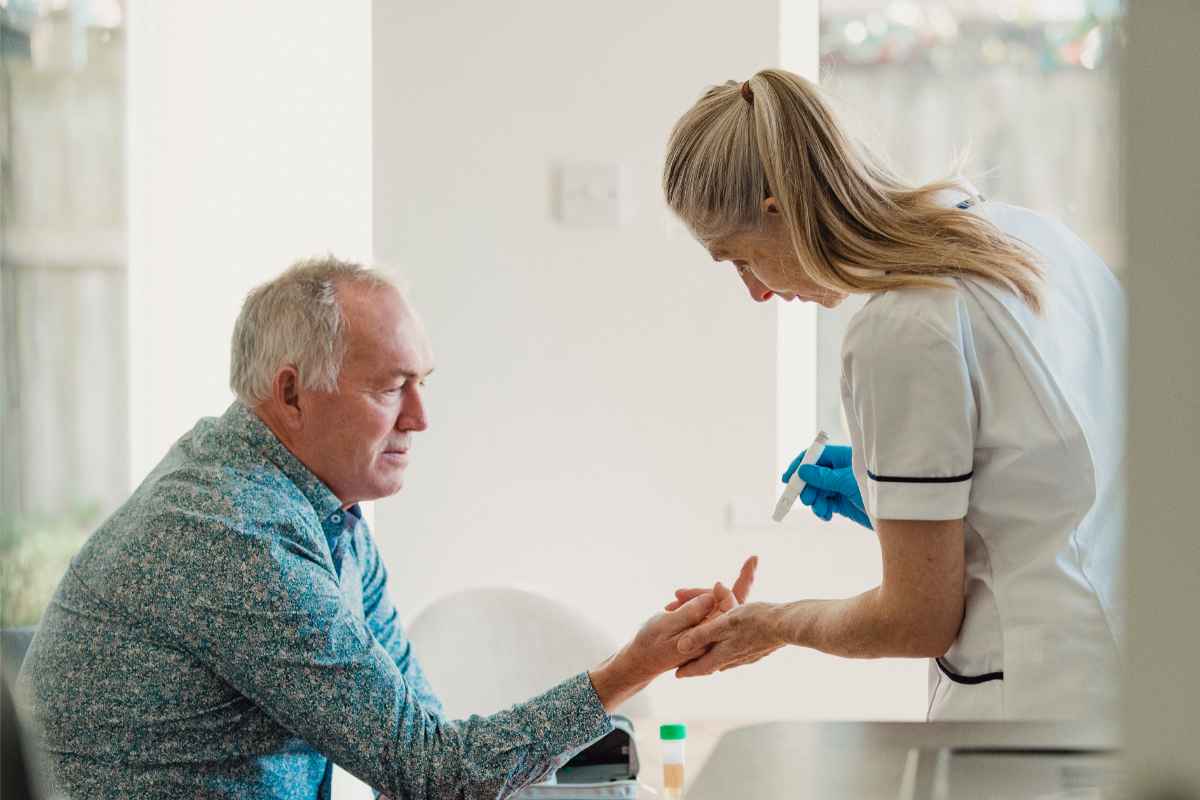 Un uomo che si fa misurare il diabete da una infermiera