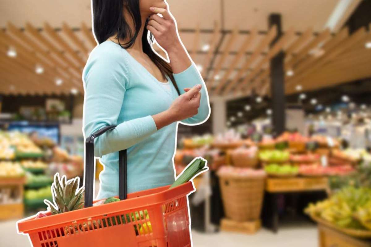 donna pensiero con il cestino della spesa nel supermercato