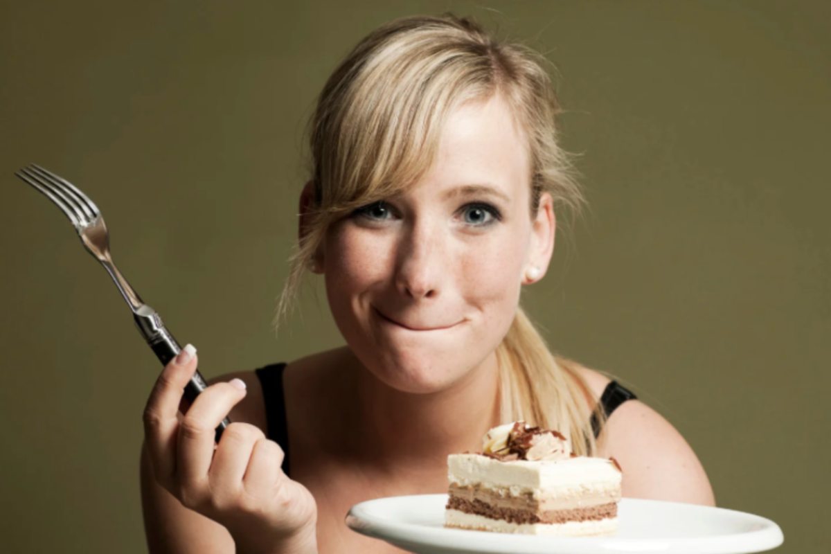 donna con in mano una forchetta e davanti una fetta di torta