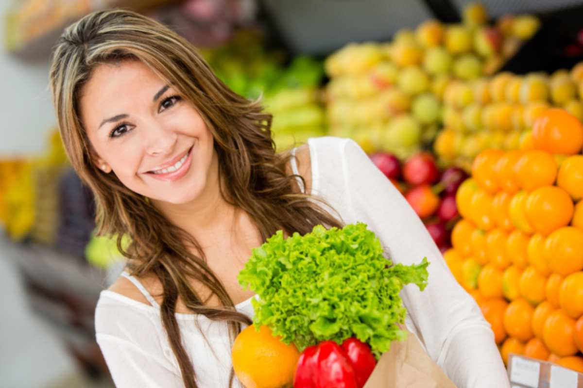 donna al supermercato con una busta piena di verdure