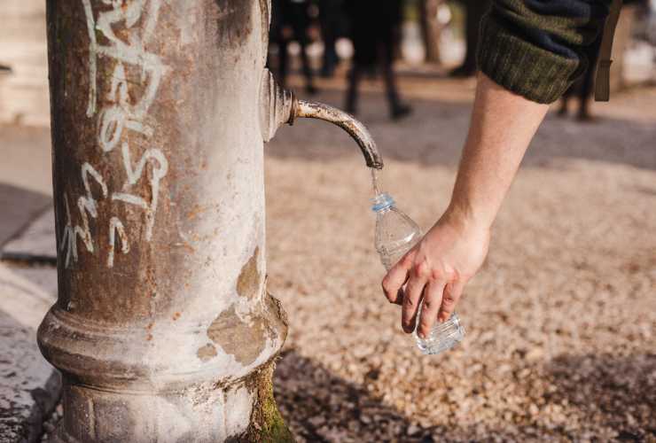 riempire la bottiglietta di acqua a una fontanella
