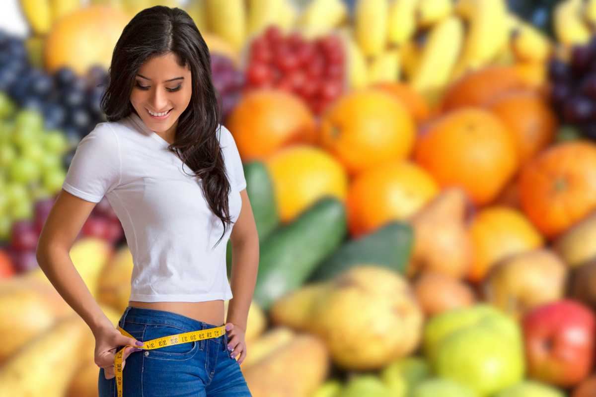 ragazza che si misura i cm della vita e frutta mista