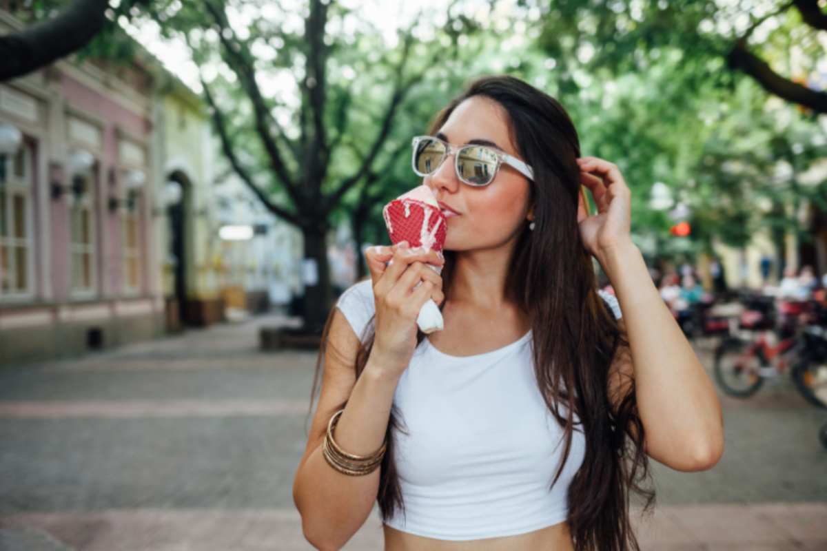 donna che mangia un cono gelato mentre passeggia per strada