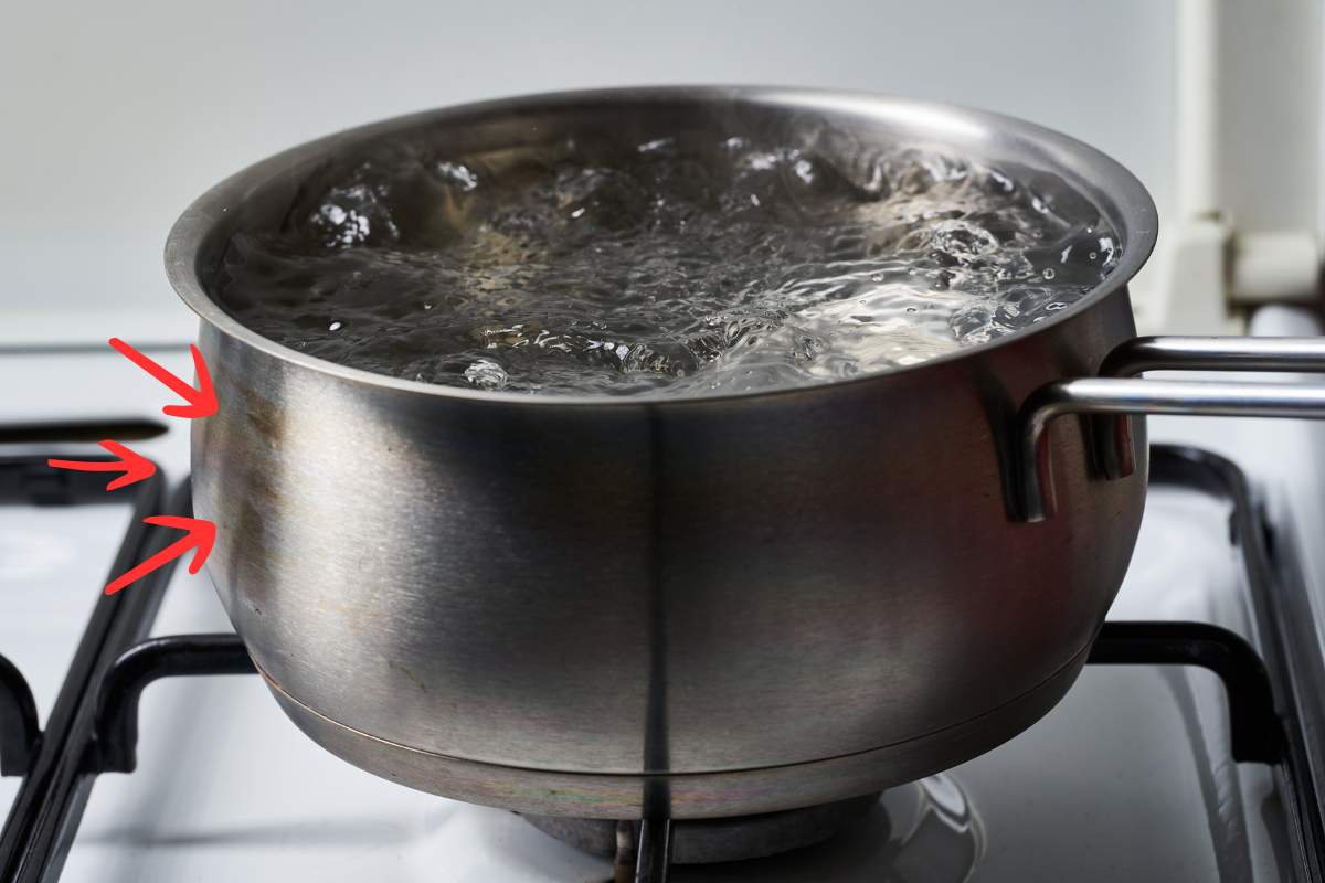 pentola rovinata con acqua che bolle su fornello