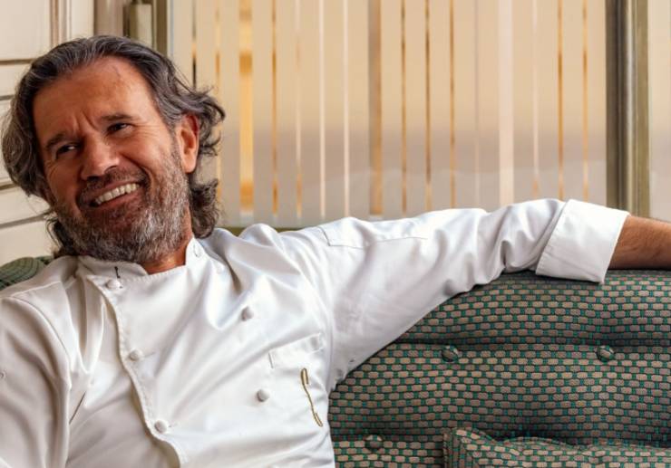 lo chef carlo cracco che sorride seduto sul divano