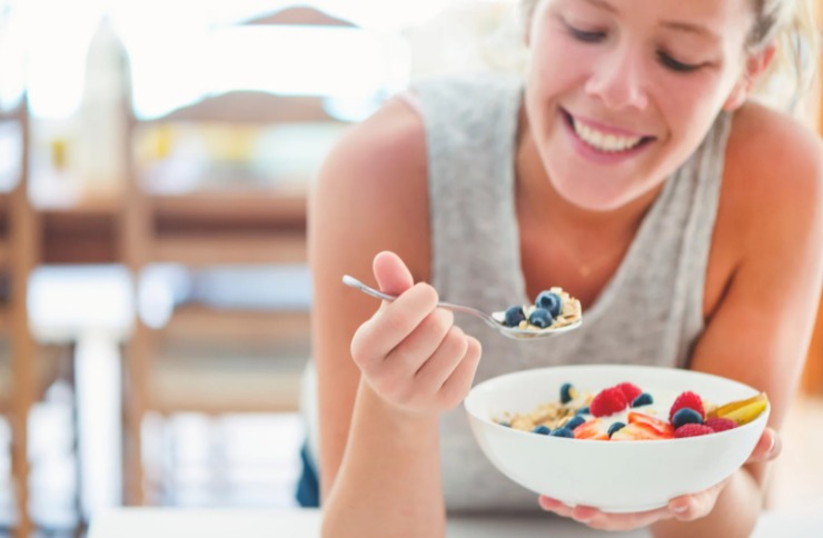 donna che mangia una tazza di cereali con frutta