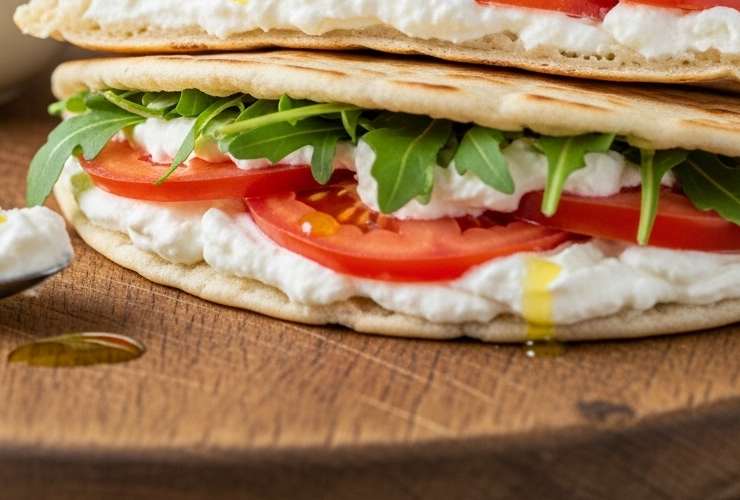 piadina ripiena di pomodori e stracchino su tagliere