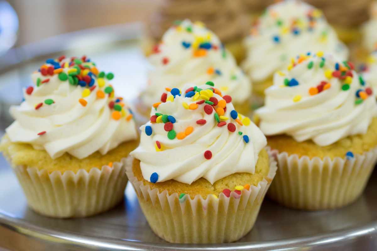 Cupcake sparsi su un vassoio guarniti con crema e codette colorate