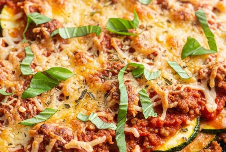 primo piano di lasagna di zucchine con formaggio fuso e pomodoro