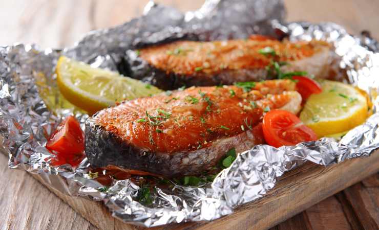 salmone pomodorini e limone nella carta stagnola su tagliere