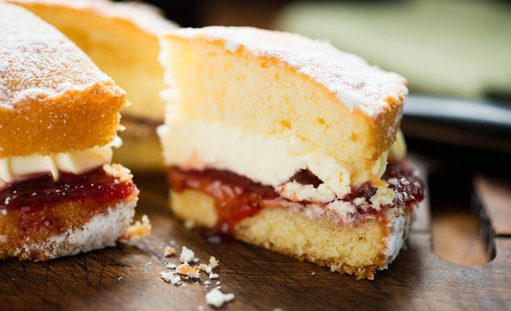 torta di pan di spagna con panna e lamponi tagliata