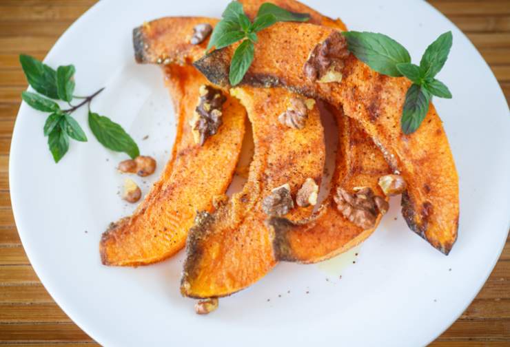 zucca arrostita con erbe aromatiche in piatto bianco