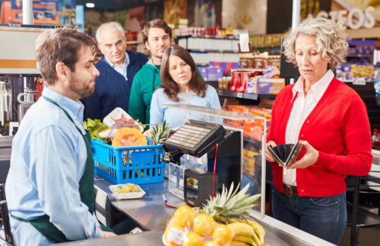 donna alla cassa del supermercato che cerca i soldi nel portafoglio