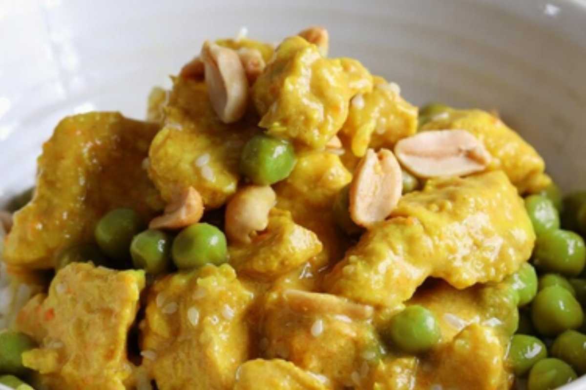 Bocconcini di pollo e piselli con arachidi in una ciotola visti da vicino