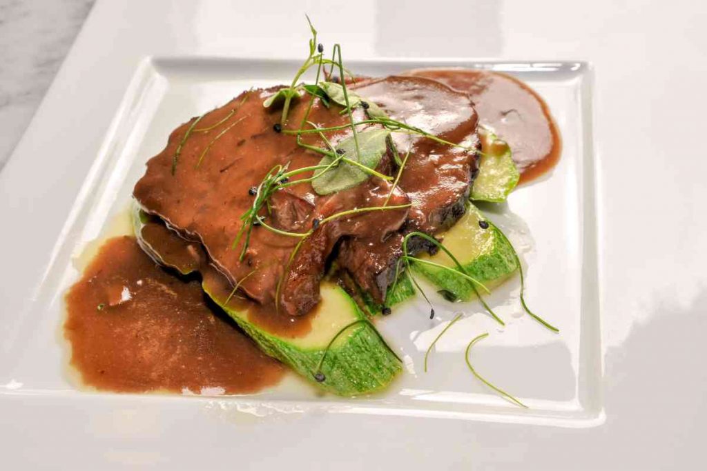 un piatto con fette di brasato al barolo contornate da zucchine