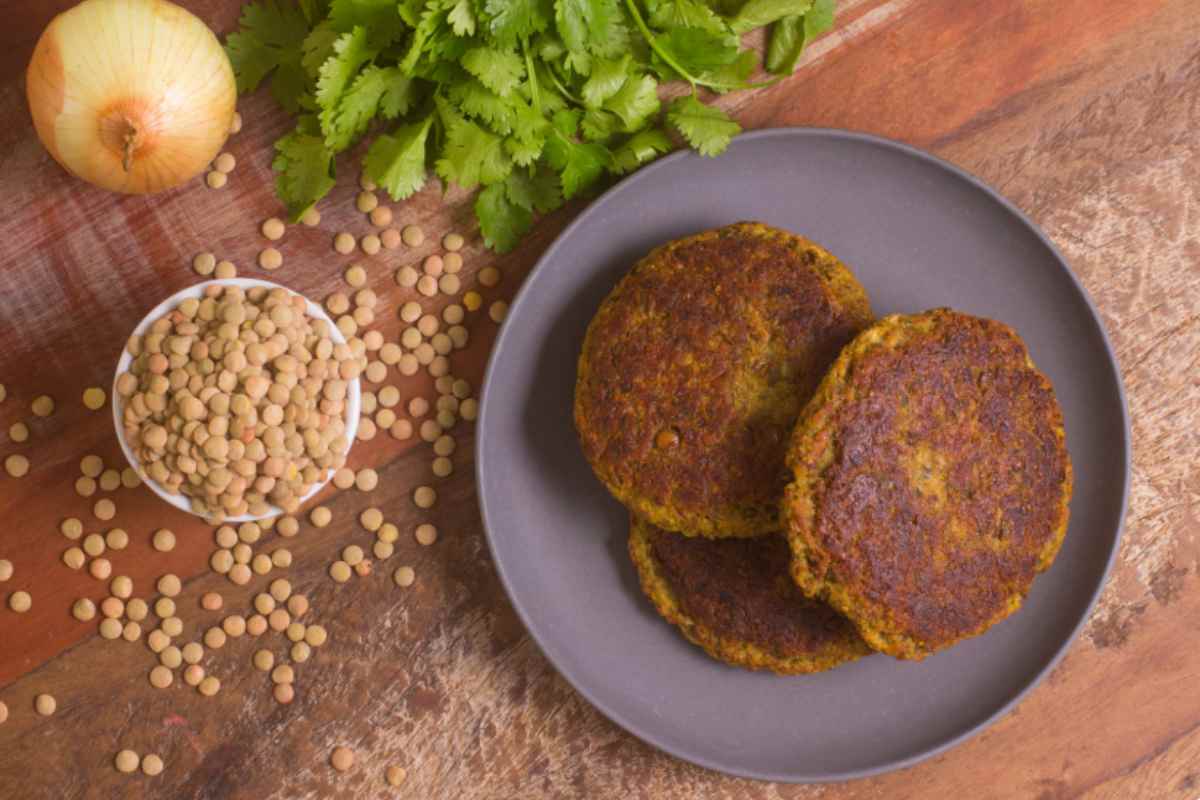 Burger di lenticchie in un piatto con lenticchie secche e prezzemolo