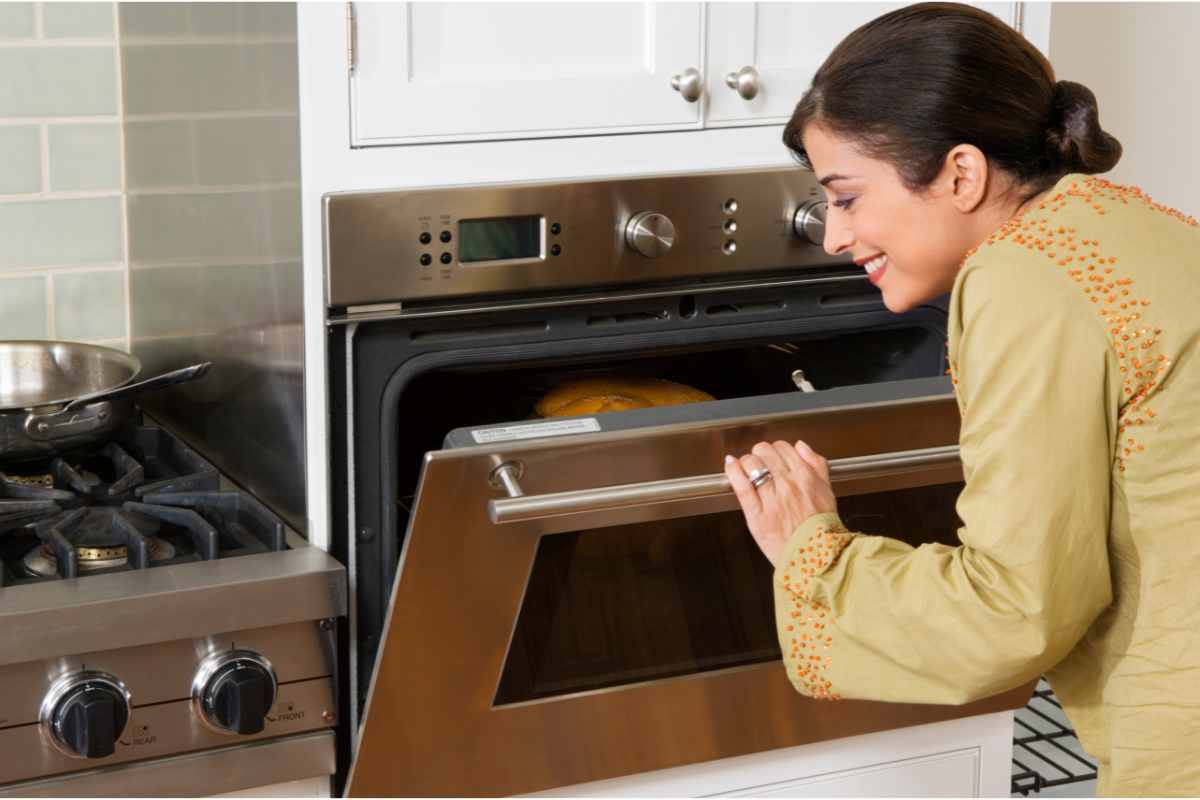 Una donna davanti ad un forno aperto