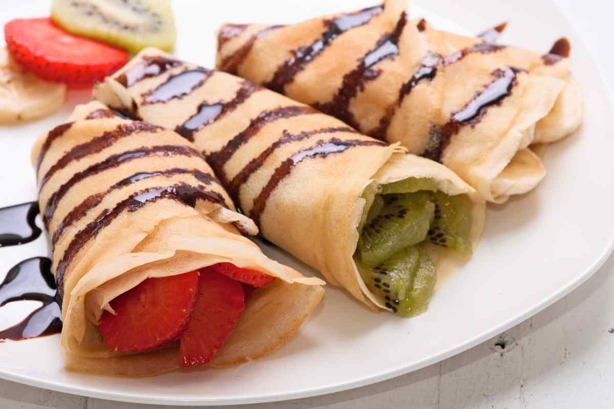 piatto con tre crepes senza burro farcite con ripieni diversi: fragole, kiwi e banane