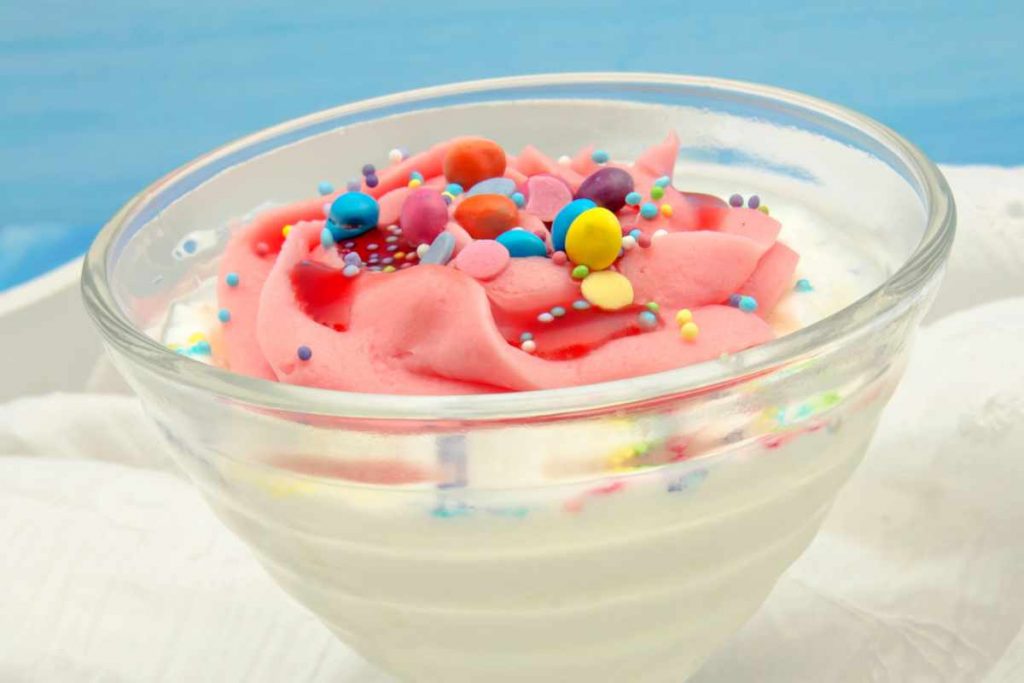una coppa con crema di yogurt e crema di fragole con smarties